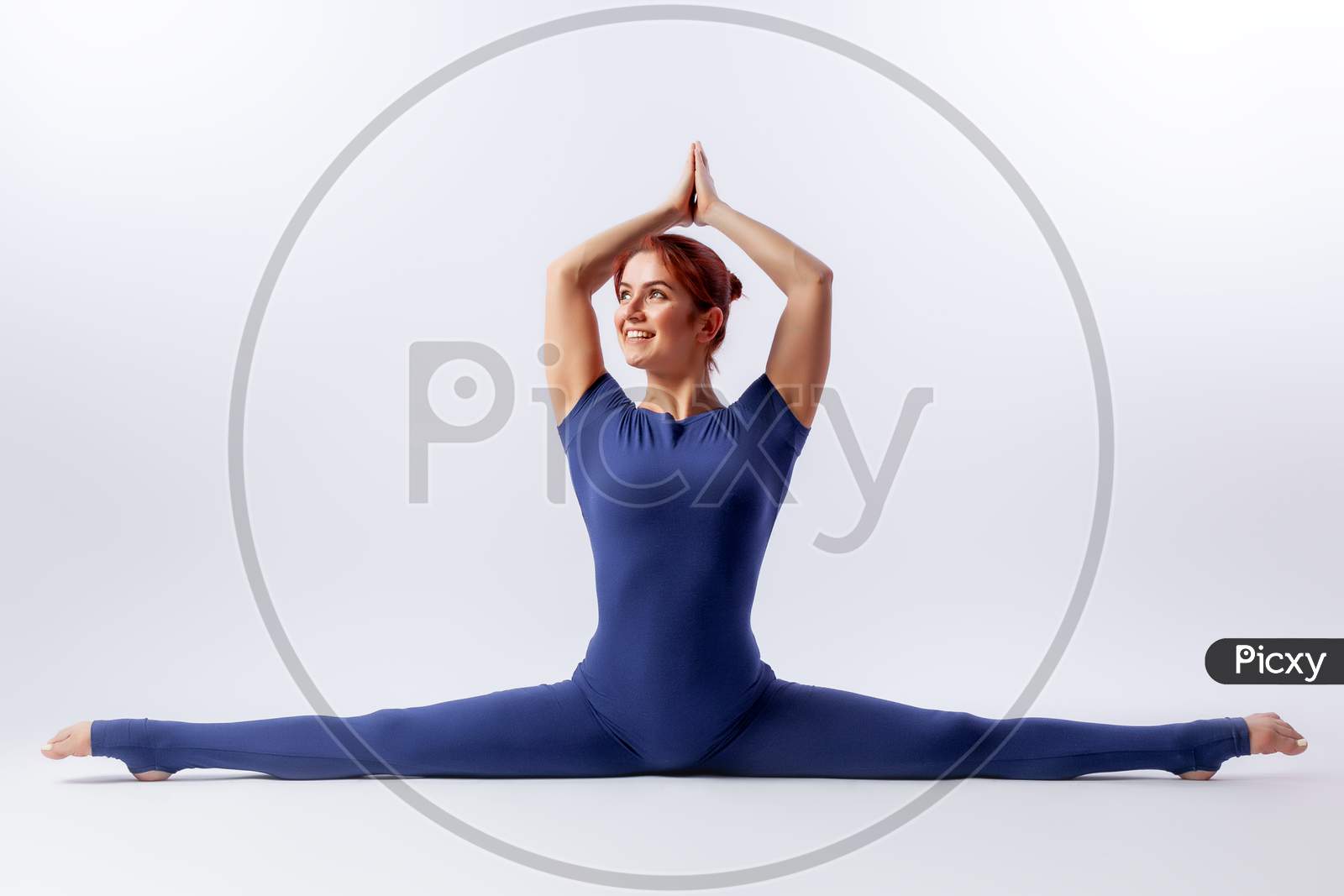Beautiful Slim Woman In Sports Overalls  Doing Yoga, Standing In An Asana Pose - Twine  On White  Isolated Background. The Concept Of Sports And Meditation. Training For Stretching And Yoga