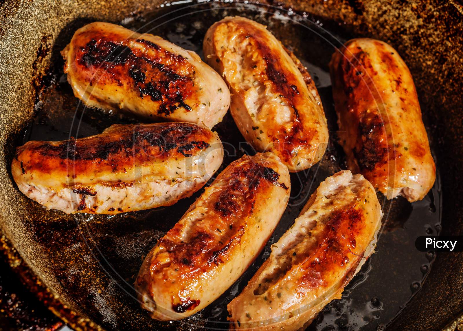 Six burnt fried German hunting sausages in a burnt frying pan