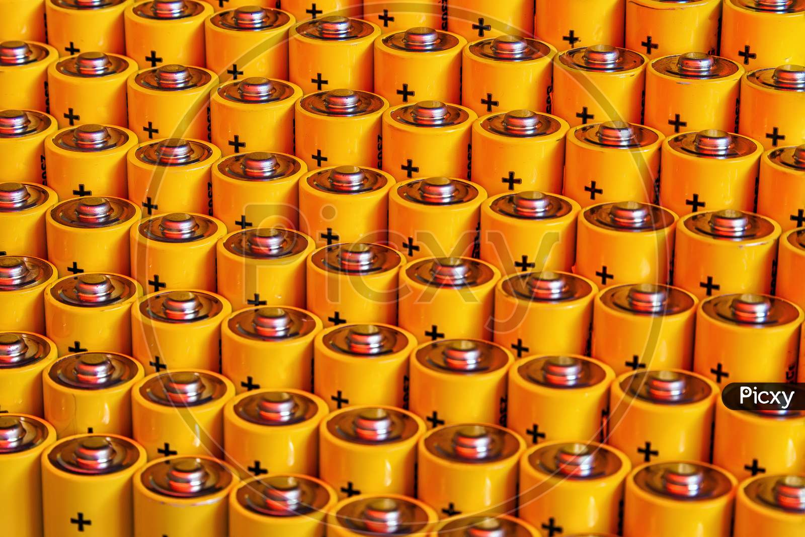 Close View Of Batteries Alkaline 1.5 Volts In Size Aa Several Batteries In Rows.A Close-Up Of The Same Yellow Batteries, Lined Up In Even Rows By Positive Charges. An Unsafe Way To Use Energy.