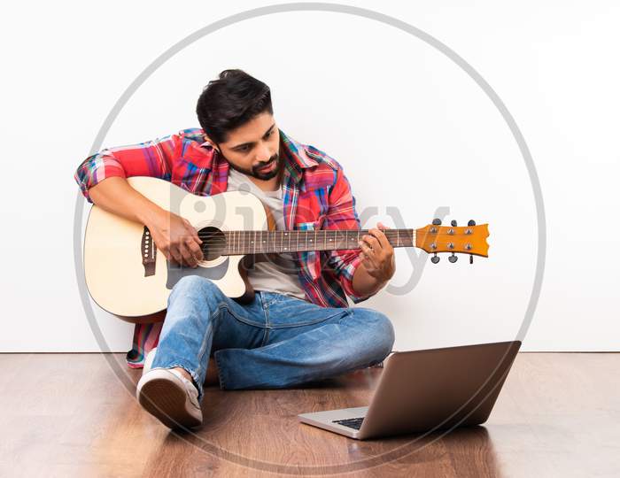 Indian Asian Young Man Playing Guitar With Laptop, Learning Or Recording Video