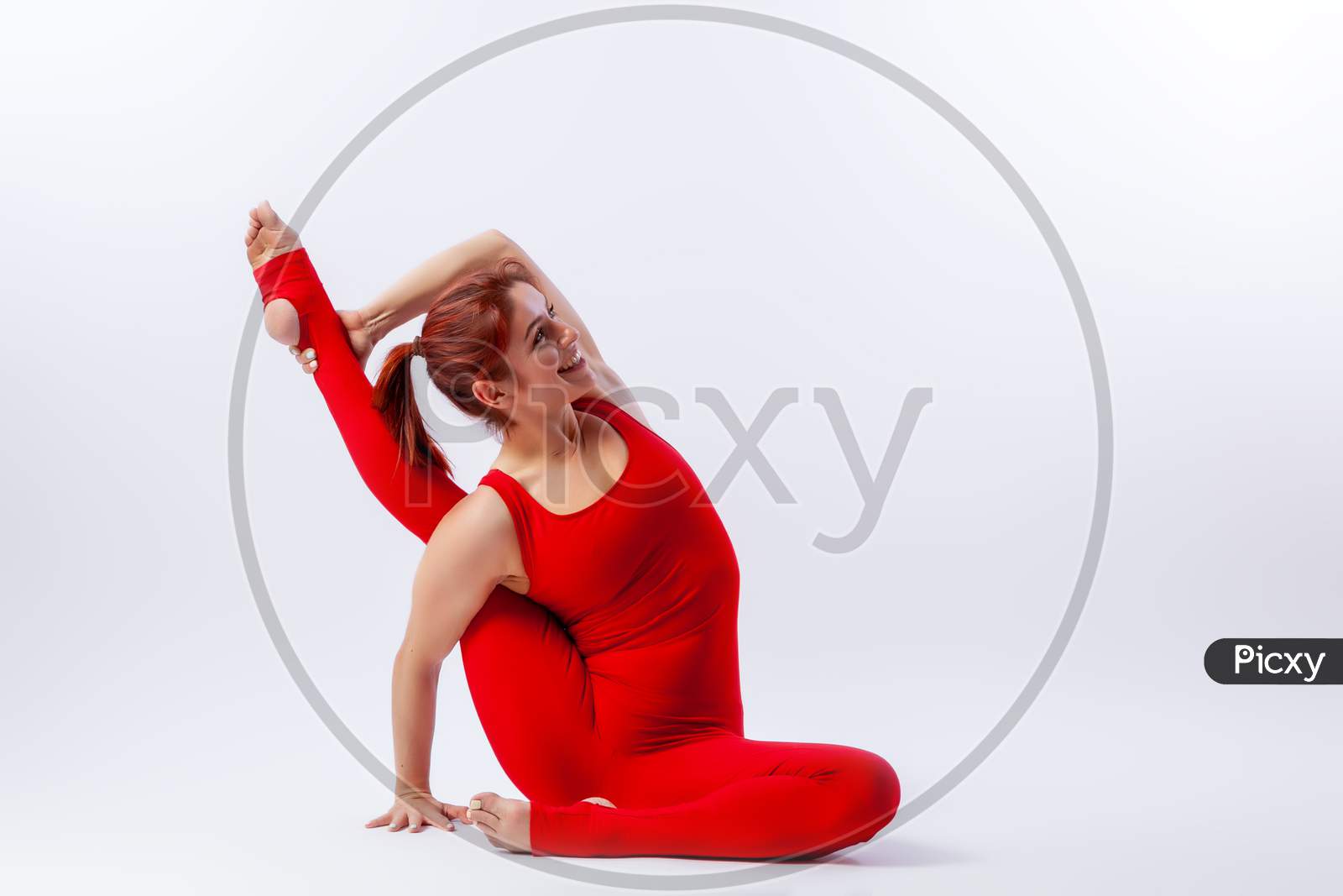Beautiful Slim Woman In Sports Overalls  Doing Yoga, Standing In An Asana Balancing Pose - Heron Pose  On White  Isolated Background. The Concept Of Sports And Meditation. Training For Stretching And Yoga