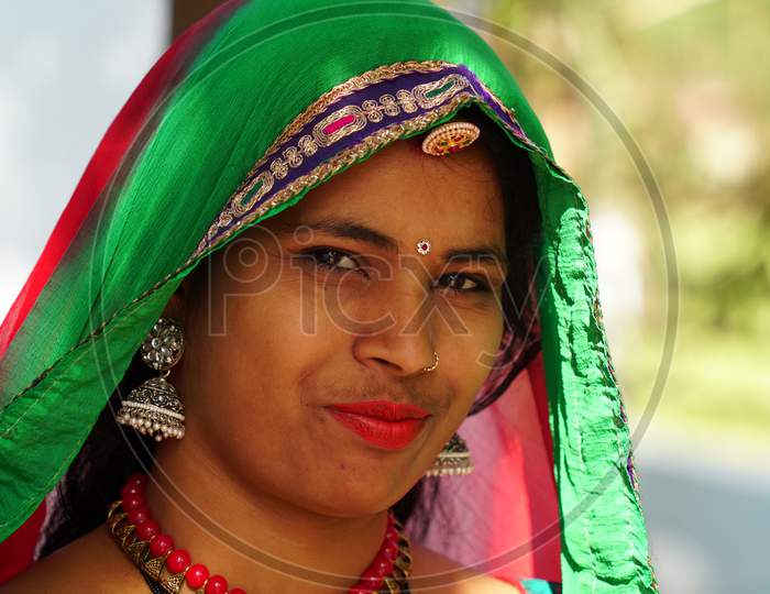 Beautiful Indian Woman In Traditional Attire. Woman With Pink Lips And Covering Head With Green Saree. Modern Woman With Costumes And Jewellery.