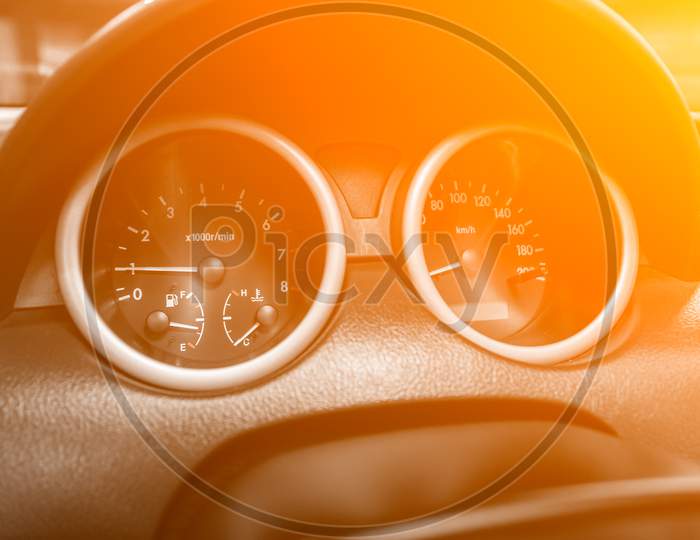 New Car Interior Details. Speedometer, Tachometer And Steering Wheel Under The Yellow And Orange Neon Color