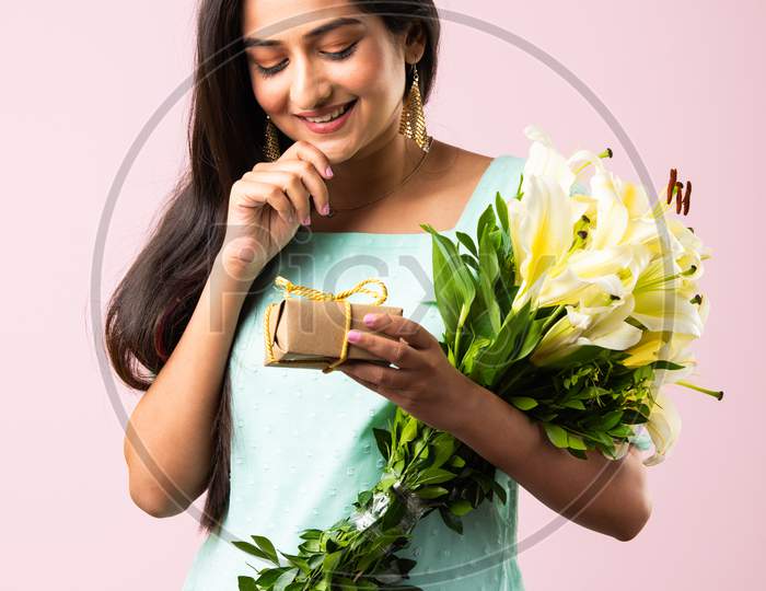 Indian Pretty Girl Opens Gift While Holding Flower Bouquet