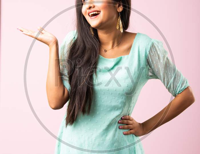 Indian Asian Young Girl Surprised And Pointing Or Advertising With Fingers Against Pink Background