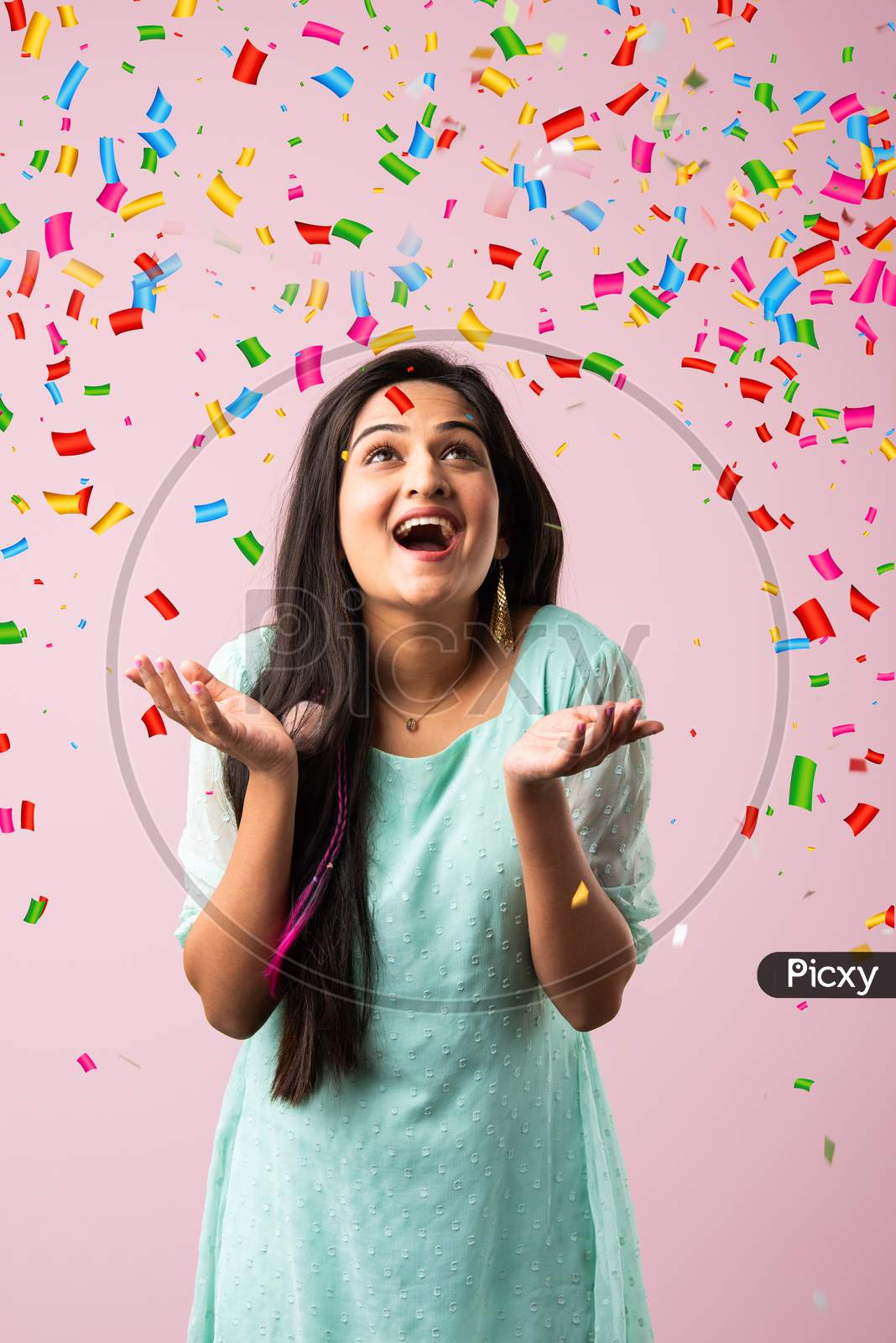 Pretty Indian Asian Young Woman With Joyful Expressions As Glitter Falling On Her Head Against Pink