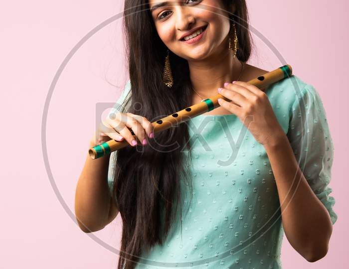Indian Asian Pretty Young Woman Or Girl Plays Flute Against Pink Background