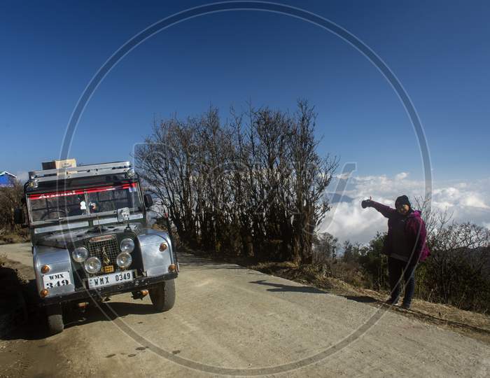 20 March, 2020, Sandakphu, West Bengal, India: A Female Traveller Standing Beside A Old Land Rover Car At Sandakphu, West Bengal.