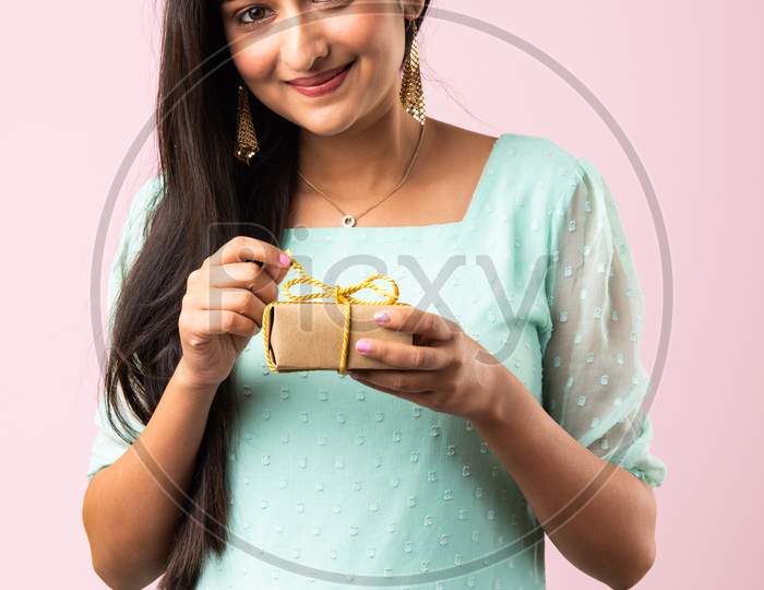 Indian Girl Or Woman With Gift Box Against Pink Background