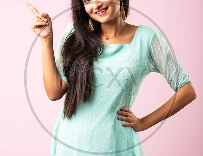 Indian Asian Young Girl Surprised And Pointing Or Advertising With Fingers Against Pink Background