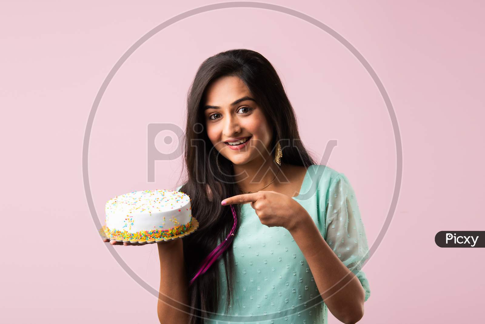 Pretty Indian Asian Woman Holding Decorated Cake Against Pink Studio Background