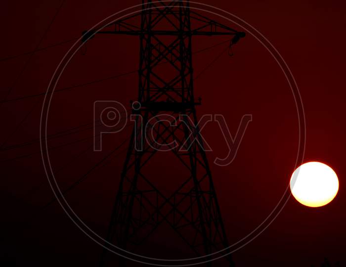 Beautiful Picture Of Electricity Tower And Big Orange Sun In Background. Selective Focus On Subject