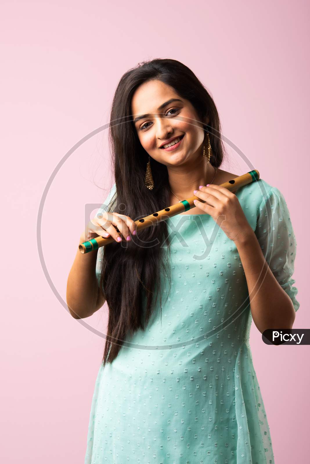 Indian Asian Pretty Young Woman Or Girl Plays Flute Against Pink Background