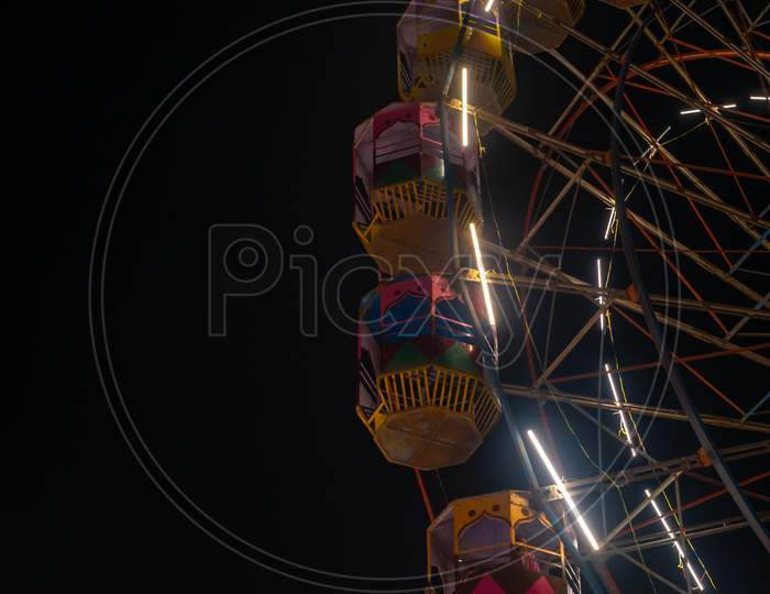A Colourful Giant Wheel At Amusement Park Illuminated At Night