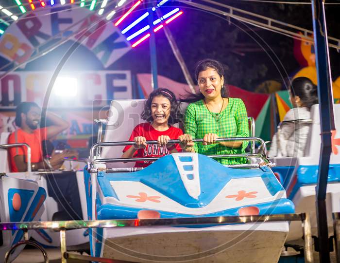 Indian Family Enjoying Carousel Ride  At Amusement Park