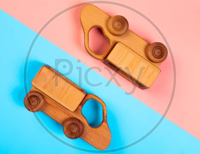 Minimalistic Flat Lay With A Wooden Toys Trucks On An Isolated Multicolored Vibrant Geometric Background. Toy For Entertaining Children And Parents