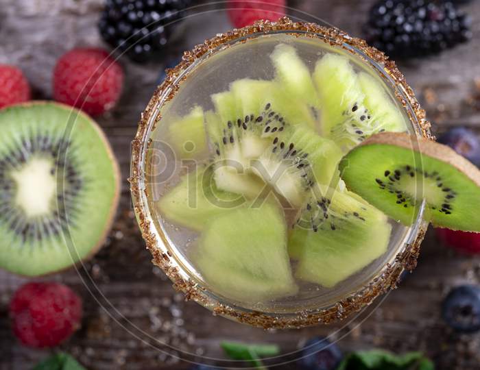 Kiwi Cocktail Seen From Above Decorated With Fruits Of The Forest On A Wooden Background