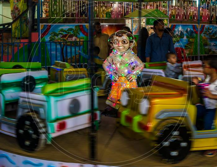 Indian Kids Enjoying Carousel Ride In A Open Car At Amusement Park