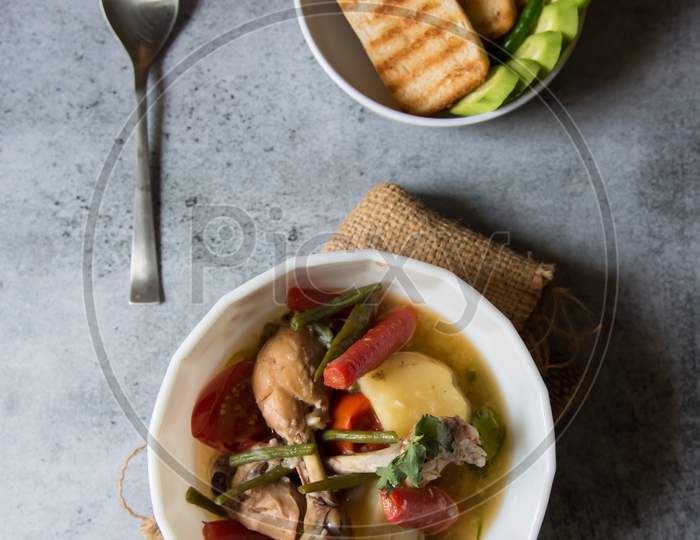 Chicken stew along with vegetables in a bowl and bread slice