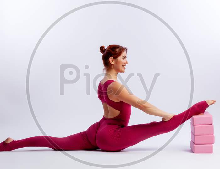 Beautiful Slim Woman In Sports Overalls  Doing Yoga, Standing In An Asana Pose - Twine Arms Over Head On White  Isolated Background. The Concept Of Sports And Meditation. Training For Stretching And Yoga