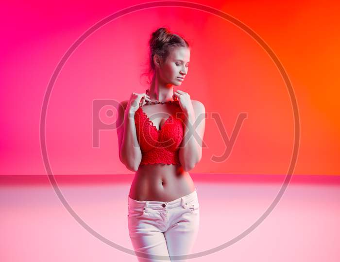 Attractive  Long-Haired Girl, Stylish Fashion. Design Art Concept. Creative Colorful Bright Neon Portrait . Beautiful Girl In Lingerie And Jeans Posing. Cinematic Night Portrait Of Woman In  Neon.