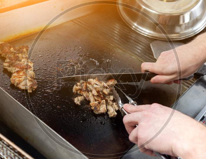 Step By Step Cooking Chicken: A Man In An Apron Cuts Slices With A Knife On A  Glove. Cooking Burritto And Shawarma