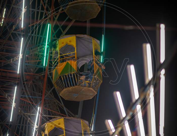 Unidentified Kid Waving From Colourful Giant Wheel At Amusement Park Illuminated At Night In India