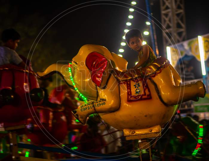 Indian Kids Enjoying Carousel Ride In Elephant At Amusement Park