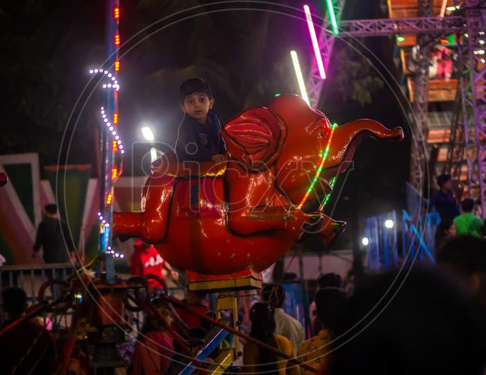 Indian Kids Enjoying Carousel Ride In Elephant At Amusement Park