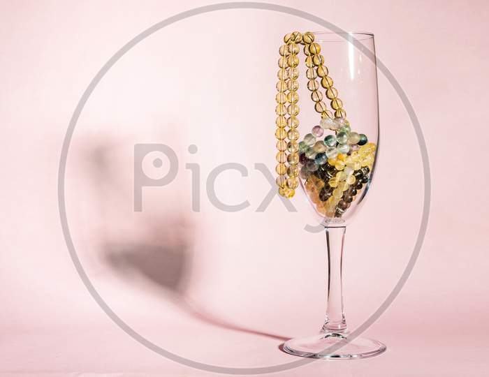 A yellow citrine gemstone  female necklase made of spherical transparent  beads in a wineglass.
