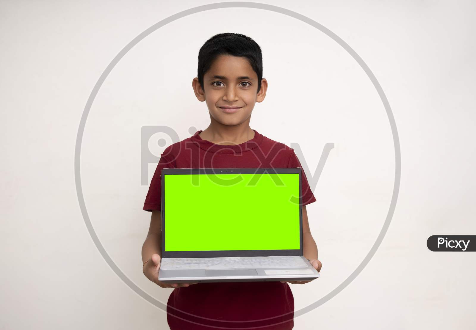 Young Indian Kid Holding A Laptop With Green Screen And Standing On A White Isolated Background With Copy Space.