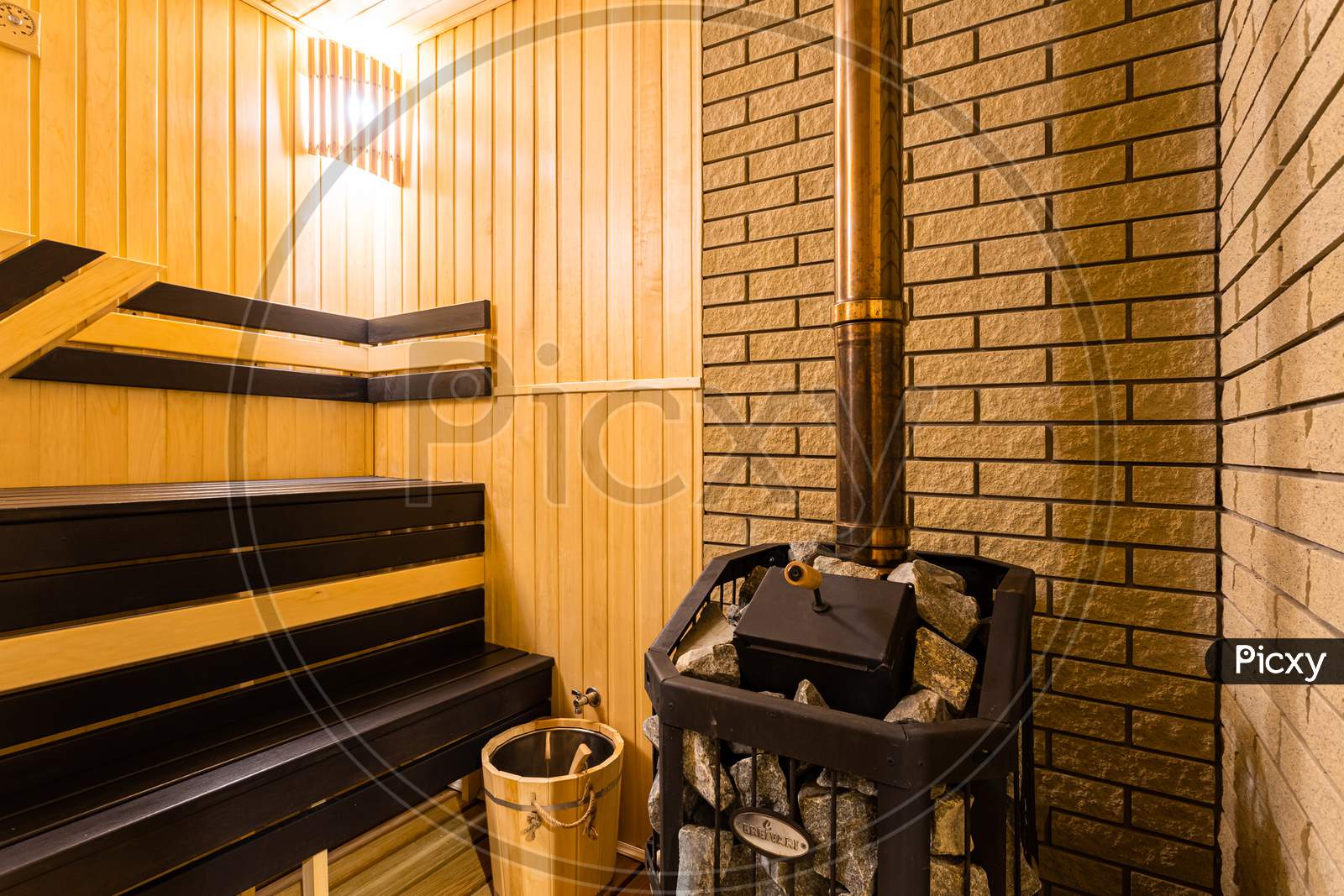 A Close-Up Of A Wooden Sauna, A Bath With A Large New Metal Stove And Benches With Beautiful Lamps In A Country House