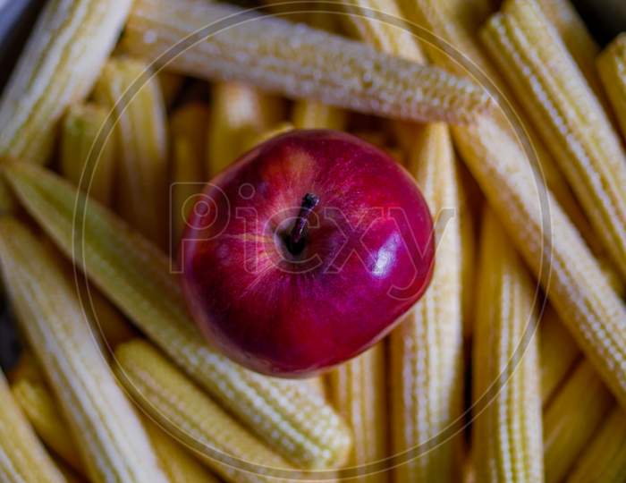 Fresh Apple And Baby Corns Arranged In A Basket
