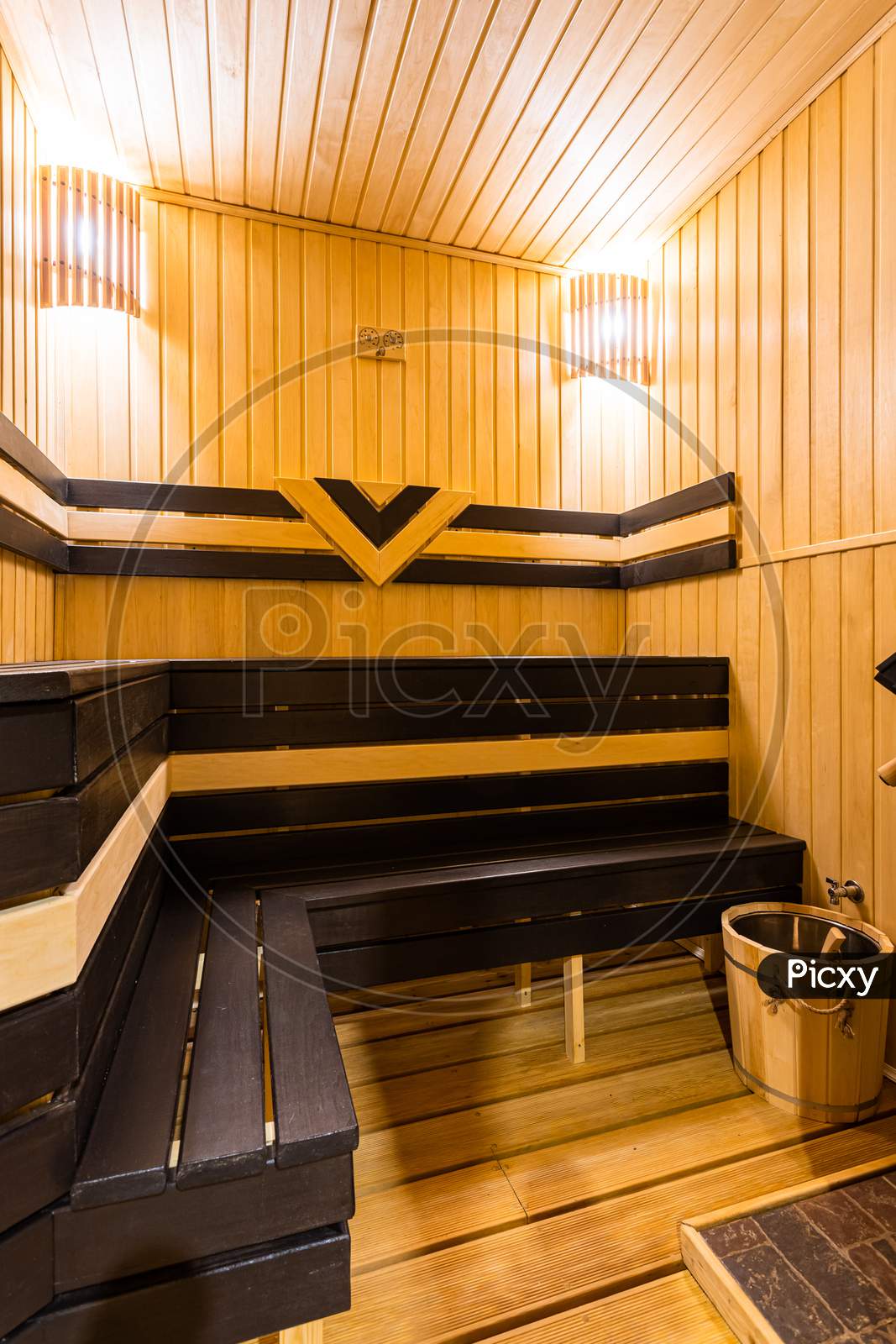 A Close-Up Of A Wooden Sauna, A Bath With A Large New Metal Stove And Benches With Beautiful Lamps In A Country House