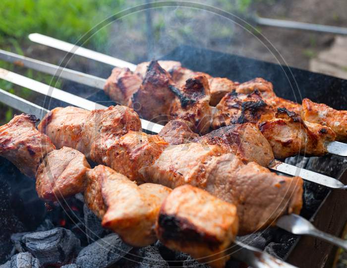 A Close-Up Of The Pies Of Pork In  Sauce Is Fried In A Grill. Preparation Of A Shish Kebab On A Summer Day