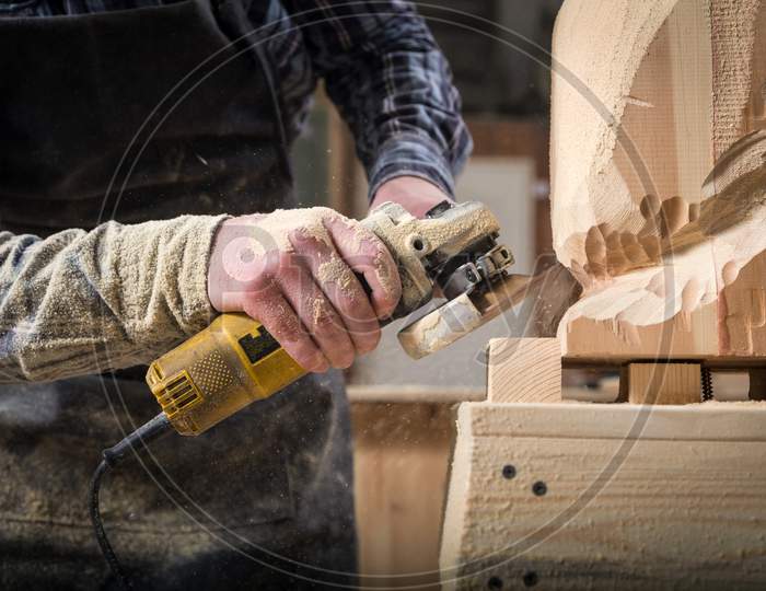 Close Up Experienced Carpenter In Work Clothes And Small Buiness Owner Processes The Board With An Angle Grinder On The Table Is A Hammer And Many Tools