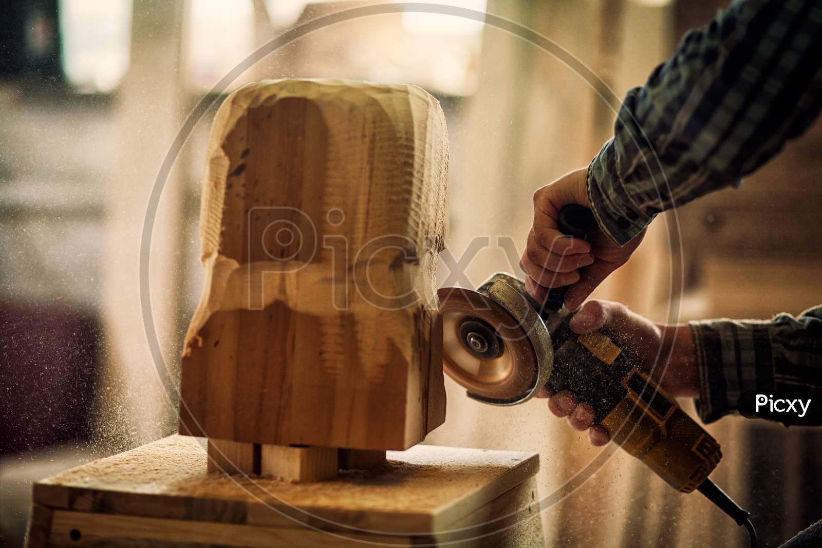 Close Up Of A  Carpenter In Work Clothes And Small Buiness Owner Working In Woodwork Workshop, Processes The Board With An Angle Grinder , On The Table Is A Hammer And Many Tools