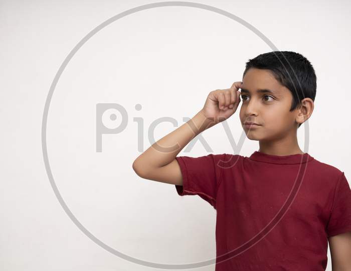 Young Indian Kid Showing Thumbs Up Into The Camera While Smiling. Small Kid Education Concept. White Isolated Background With Copy Space.