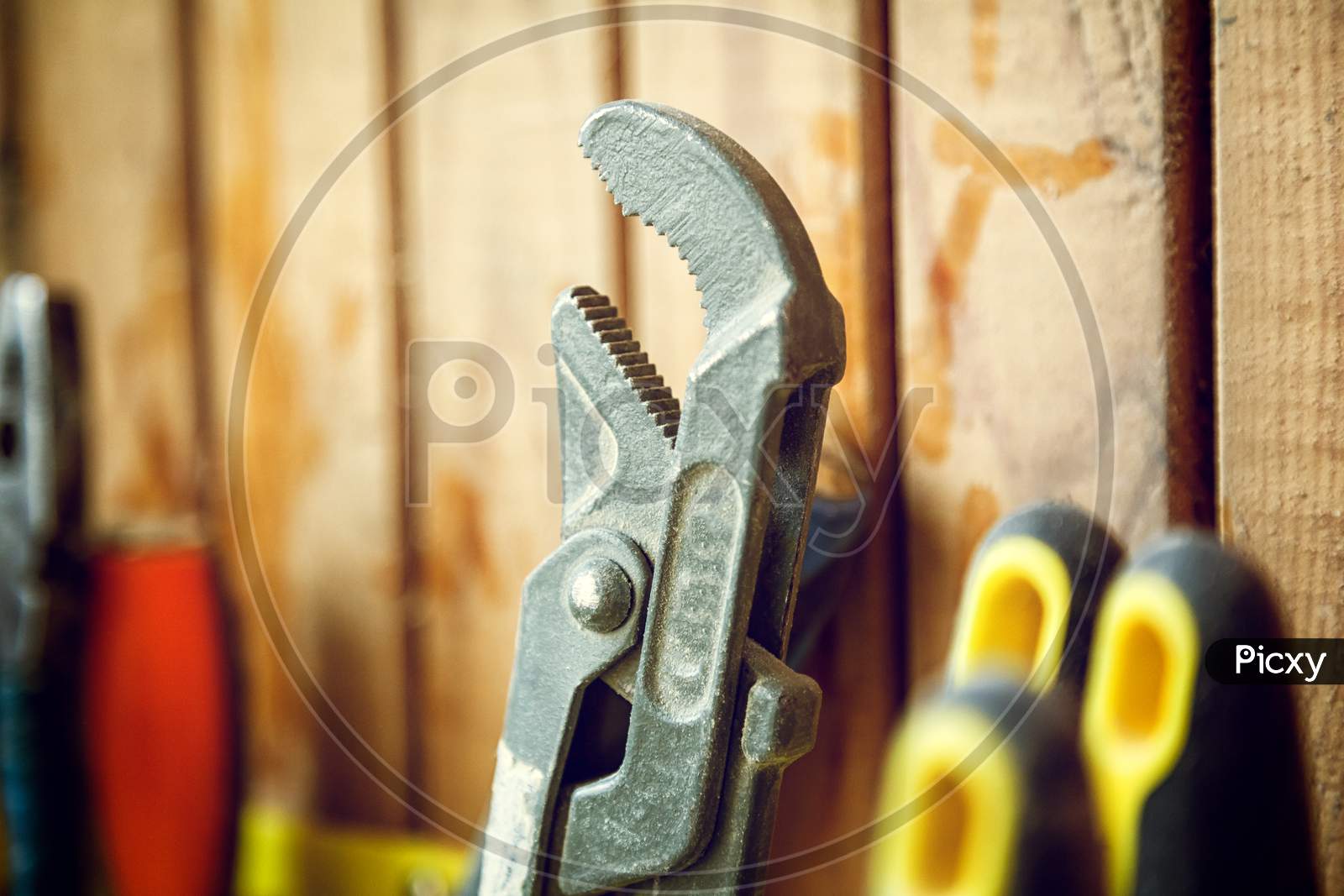 A Close-Up Of A Set Of Tools: Pliers, A Screwdriver, A Wrench On A Yellow Stand