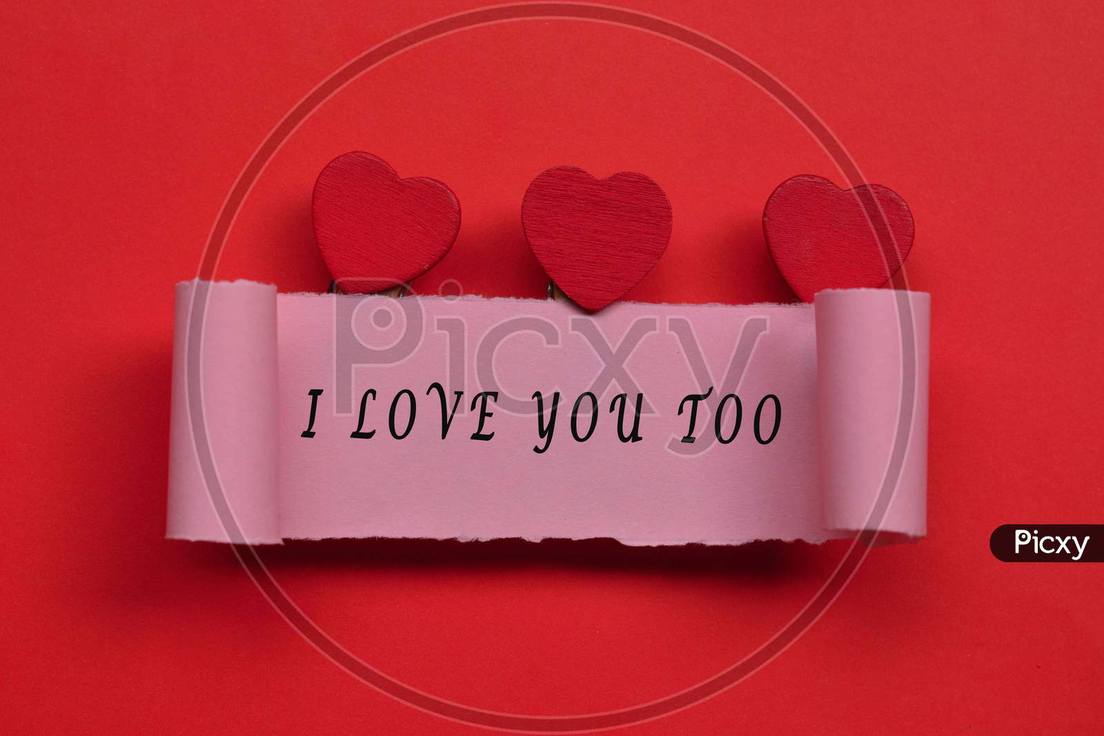 I Love You Too Label On Torn Paper With Heart Shape On Red Background