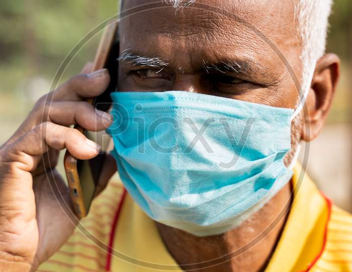 Pan Shot Of Old With Medical Face Mask Busy Talking In Mobile Phone - Concept Of Senior People Using Technology, Communication And Lifestyle.