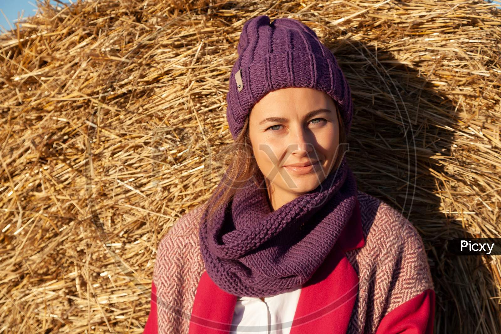 Portrait Of A Beautiful Young Model In Knitted Hat  And Warm Clothes Enjoy Day, On Background Field In  Sunny Autumn Day . Autumn Warm Photo. Woman Smiling And Look Away, Joyful Cheerful Mood.