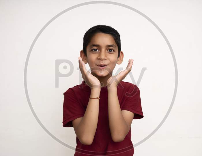 Young Indian Kid Acting Surprised White Standing On A White Wall With Copy Space. Education And Fun Concept.
