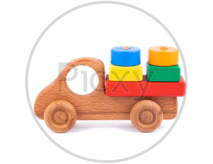 Close-Up Children'S Toy Made Of Natural Wood In The Form Of A Dump Truck  With Wooden Blocks In The Form Of Multi-Colored Geometric Shapes On A White Isolated Background. Studio Photography. Eco-Friendly Toy For Parents And Children
