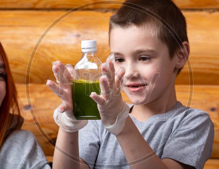 Mom And Son Are Doing Chemical Experiments, Watching The Color Change In The Bottle As A Result Of A Chemical Reaction At Home. Teaching The Basics Of Chemistry At Preschool Age