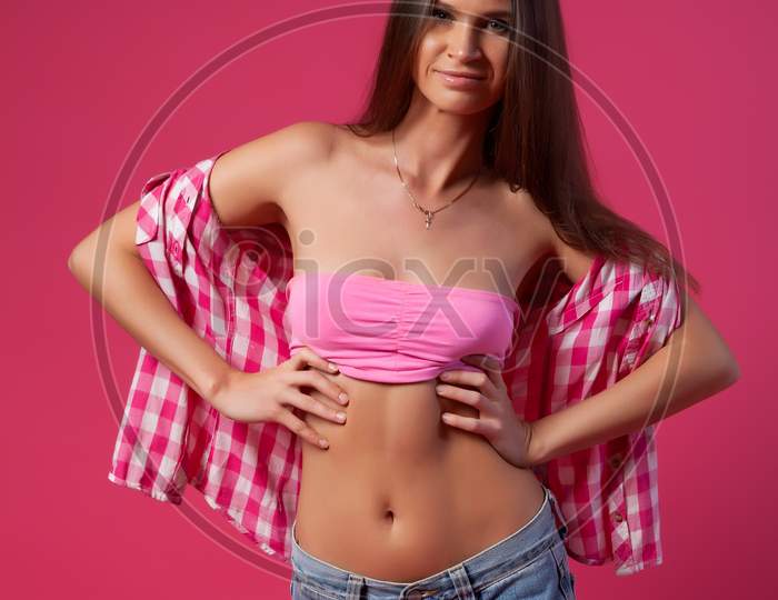 Beautiful Woman With Healthy Body Wearing In A Pink Swimsuit, Shirt And Denim Shorts On Pink Background.The Concept Of Summer Fashion Swimsuit And Relaxation. Pink And Joyful Mood.
