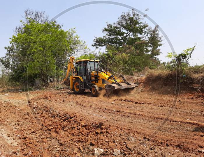 Closeup of JCB cleaning land for construction of building at forest or countryside