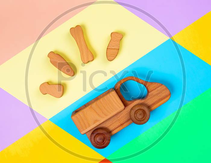 Cargo An Dchildren Delivery Concept. Wooden  Toy Truck With Bone, Carrot, Fish, Mushroom    On Isolated Multicolored Vibrant Geometric Background Top View Mockup