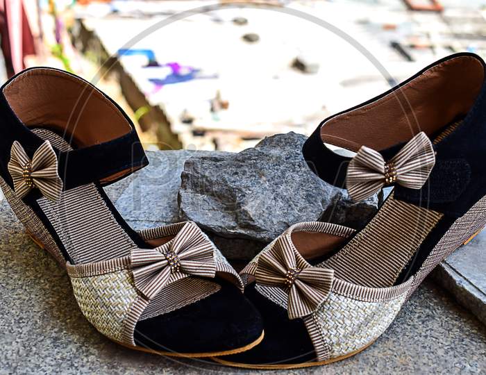 Stock Photo Of Beautiful Pair Of Black And Cream Color High Heel Sandals Displayed On Blur Background ,Kept On Table Under Bright Sunlight At Bangalore City Karnataka India.