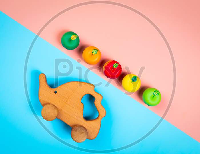 Minimalistic Flat Lay With A Wooden Toys Hedgehog With Colorful Apples  On An Isolated Multicolored Vibrant Geometric Background. Toy For Entertaining Children And Parents